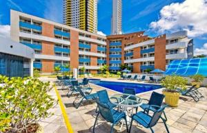Un complejo con piscina y sillas y un edificio. en Flat em Ponta Negra Natal/RN, en Natal