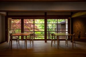 two tables and chairs in a room with windows at Shiroyamakan in Shirakawa