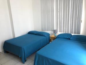 2 camas en una habitación con sábanas azules en Flor de Lis Beach House, villa vacacional, en Playas