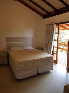 ein Schlafzimmer mit einem Bett in einem Zimmer mit einem Fenster in der Unterkunft Cruz House in Florianópolis