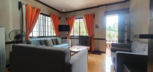 a living room with two couches and two windows at JCGA Apartments (Angelo's Burnham) in Baguio