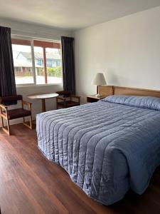 ein Schlafzimmer mit einem großen Bett mit einer blauen Decke in der Unterkunft Captain John's Motel in Charleston