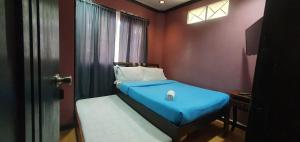 um pequeno quarto com uma cama azul e uma janela em JCGA Apartments (Angelo's Burnham) em Baguio