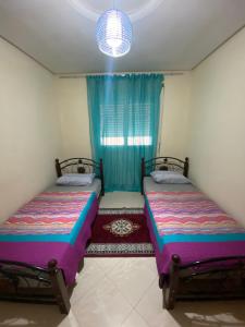 two beds in a small room with a window at Appartement kenzi Beach in Tangier
