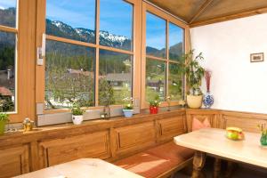 a room with windows and tables and potted plants at Gaestehaus Richter in Oberammergau