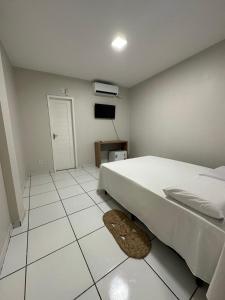 um quarto branco com uma cama e piso em azulejo em Pousada Central dos Lençóis em Barreirinhas