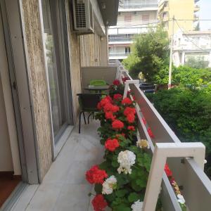 アテネにあるMaria's Cozy apartment in Palaio Faliroの赤と白の花とテーブル付きのバルコニー