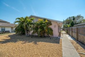 a house with palm trees next to a fence at Luxury Villa 3 Blocks from the Beach with Pool a Fire Pit and Outdoor Oasis in Cape Canaveral