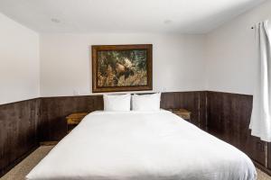 a bedroom with a large white bed with a painting on the wall at Alpine #2 in West Yellowstone
