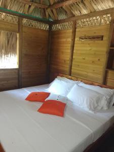 Cama en habitación de madera con 2 almohadas rojas en Cabaña Wiwa Tayrona, en Santa Marta