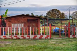 une maison en bois avec une clôture et une aire de jeux dans l'établissement Cabaña/bungalow a orillas de Laguna. vacacional, à Catazajá