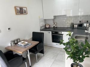 cocina con mesa de madera y sillas negras en Dannifar Guest House, en Londres