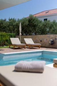 - une piscine avec 2 chaises longues à côté dans l'établissement Luxury Villa Favela with heated pool, à Trogir