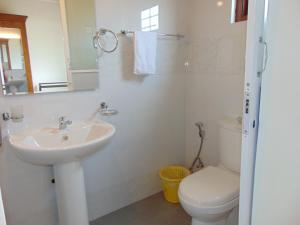 La salle de bains blanche est pourvue d'un lavabo et de toilettes. dans l'établissement KOON COTTAGE, à Kandy