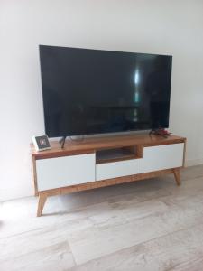 a large flat screen tv on a wooden entertainment center at Duplex Pinamar norte frente al bosque in Pinamar