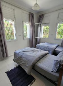 2 letti in una camera da letto con due finestre di Maison Sidi bouzid a Sidi Bouzid