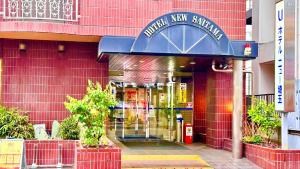 een winkel voor een rood bakstenen gebouw met een blauwe ingang bij Hotel New Saitama in Saitama