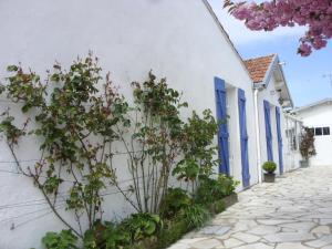een wit gebouw met blauwe deuren en bloemen op een straat bij Maison La Bernerie-en-Retz, 5 pièces, 8 personnes - FR-1-612-77 in La Bernerie-en-Retz