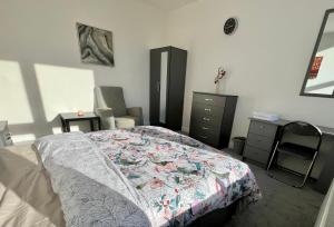 a bedroom with a bed and a chair and a dresser at 2 Bedroom Flat Ground Floor in Town Center in Wellingborough