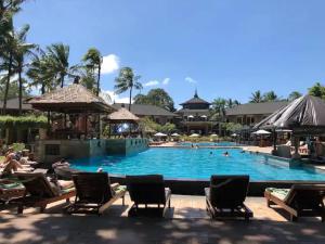a pool at a resort with people sitting in chairs at Apartment 6450 at Jayakarta Residence Bali in Legian