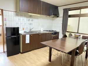 a kitchen with a table and a black refrigerator at Hiroshima Danbara LiBPLUS in Hiroshima