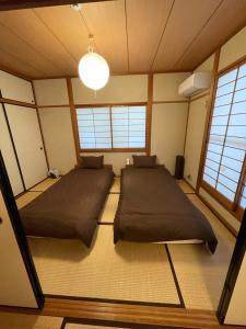 two beds in a room with two windows at Hiroshima Danbara LiBPLUS in Hiroshima