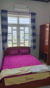 Cama rosa grande en habitación con ventana en Eo Gió Motel, en Hưng Lương