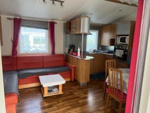 un soggiorno con divano rosso e una cucina di Mobil-Home Blonville-sur-Mer, 3 pièces, 6 personnes - FR-1-712-60 a Blonville-sur-Mer