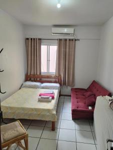 um quarto com uma cama e um sofá vermelho em APT Praia Central Itapema 90MTS do Mar em Itapema