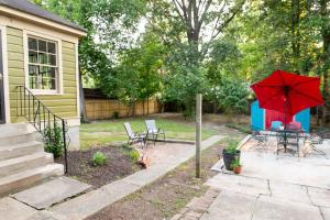 un patio con una mesa y una sombrilla roja en J Birds' Cottage Midtown Memphis en Memphis