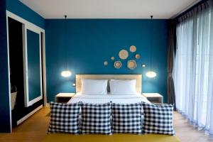 a bedroom with a bed with a blue wall at Signature Phuket Resort SHA Plus in Chalong 