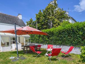 een patio met een tafel en stoelen en een parasol bij Villa Landaul, 4 pièces, 6 personnes - FR-1-479-152 in Landaul