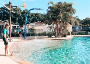 dos niños jugando en el agua en una piscina en Jervis Bay Holiday Park, en Huskisson