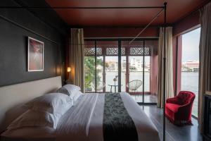 a bedroom with a large bed and a large window at Amdaeng Bangkok Riverside Hotel - SHA Plus Certified in Bangkok