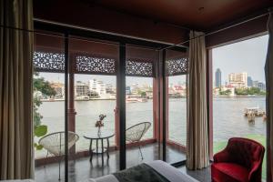 Amdaeng Bangkok Riverside Hotel - SHA Plus Certified في بانكوك: غرفة بنوافذ كبيرة مطلة على الماء