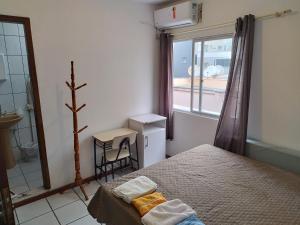 a small bedroom with a bed and a window at APT Praia Central Itapema 90MTS do Mar in Itapema