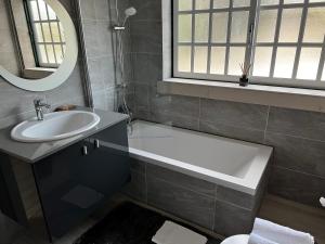 La salle de bains est pourvue d'une baignoire, d'un lavabo et d'un miroir. dans l'établissement White Guest Fátima, à Fátima