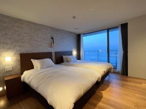 a bedroom with two beds and a large window at 3rd House Inamuragasaki in Kamakura