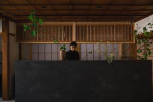 eine Person, die hinter einer Theke in einem Raum sitzt in der Unterkunft Shiroyamakan in Shirakawa-gō