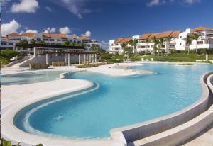 a swimming pool at a resort with houses in the background at New! Beachfront Lux Condo With Private Jacuzzi in Punta Cana +27 photos
