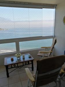 Sala de estar con mesa y sillas y vistas al océano en Departamento Costa Quilen (10 min Maitencillo), en Valparaíso