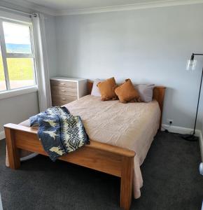 Schlafzimmer mit einem Bett mit einem Holzrahmen und einem Fenster in der Unterkunft Country Hamptons Coastal Chic with Heated Pool in Ruakaka