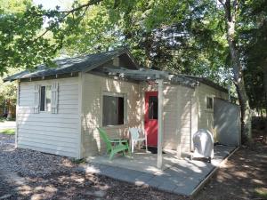 un pequeño cobertizo blanco con una silla verde y una mesa en Sleeping Bear Riverside Cabins - Cabin #4, en Honor