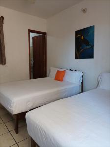 two beds in a room with white sheets at Hotel Villa Tulipanes in Zihuatanejo