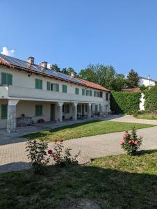 - un grand bâtiment blanc avec des fleurs dans la cour dans l'établissement Cascina cortese, à Vigliano d'Asti