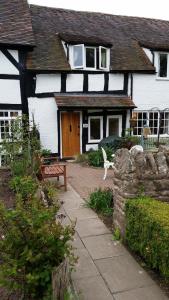 ein schwarzweißes Haus mit einer Bank davor in der Unterkunft Peel Cottage, Dilwyn in Dilwyn