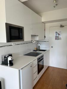 a white kitchen with a sink and a microwave at Dee Why Beach - Studio 29 Surfrider in Deewhy