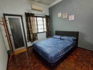 Un dormitorio con una cama azul y una ventana en Happy Home [Bandar Seri Alam], en Masai