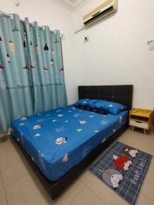 a bedroom with a bed with a blue comforter at Happy Home [Bandar Seri Alam] in Masai