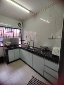 eine Küche mit einer Spüle und einer Arbeitsplatte in der Unterkunft Happy Home [Bandar Seri Alam] in Masai